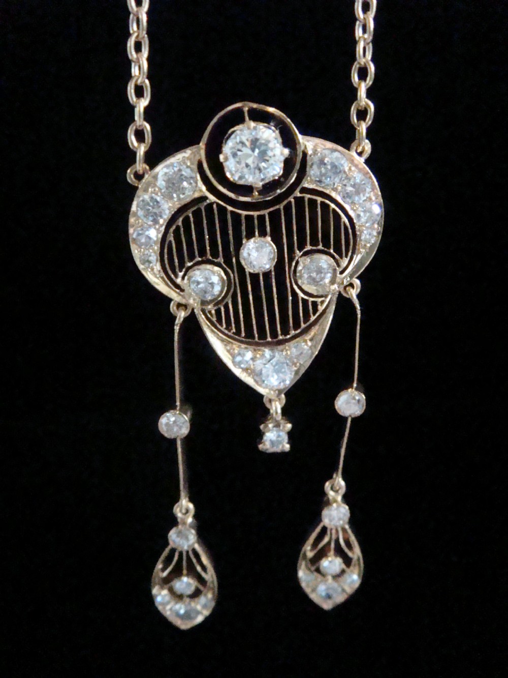 An ornate Victorian yellow gold pendant necklace set with round diamonds and black enamel accents, featuring two hanging diamond drop elements.