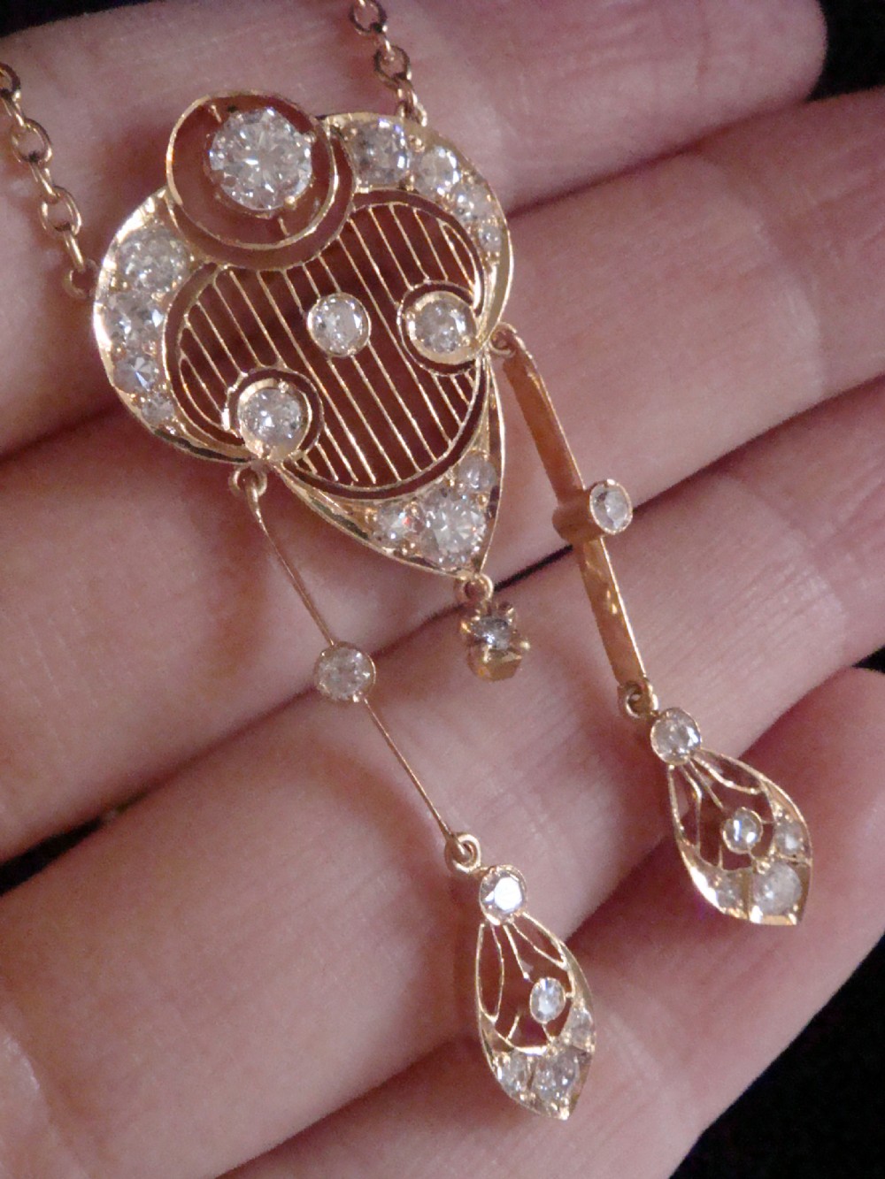 An ornate Victorian yellow gold pendant necklace set with round diamonds and black enamel accents, featuring two hanging diamond drop elements. View V