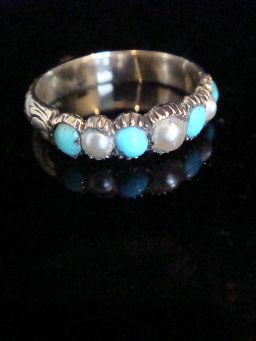 A Late Georgian 15ct gold half eternity ring featuring alternating round turquoise cabochons and pearls with hand-engraved details on the band.