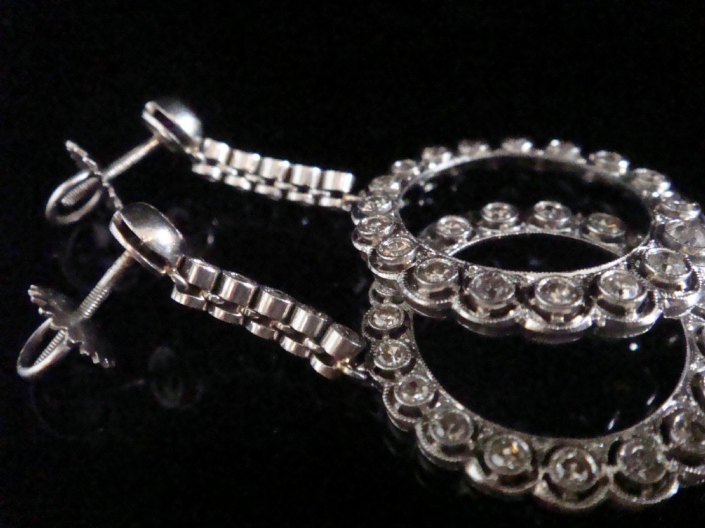 Pair of Edwardian style platinum and 18ct white gold drop earrings featuring circular halo pendants set with old cut diamonds suspended from articulated linear stems. View V