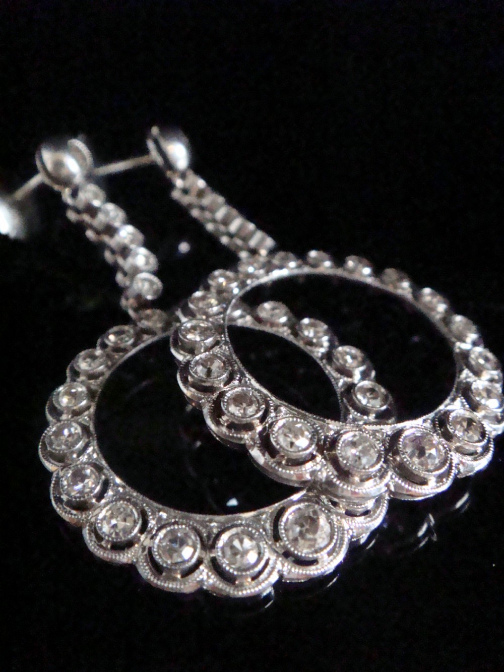 Pair of Edwardian style platinum and 18ct white gold drop earrings featuring circular halo pendants set with old cut diamonds suspended from articulated linear stems. View VIII