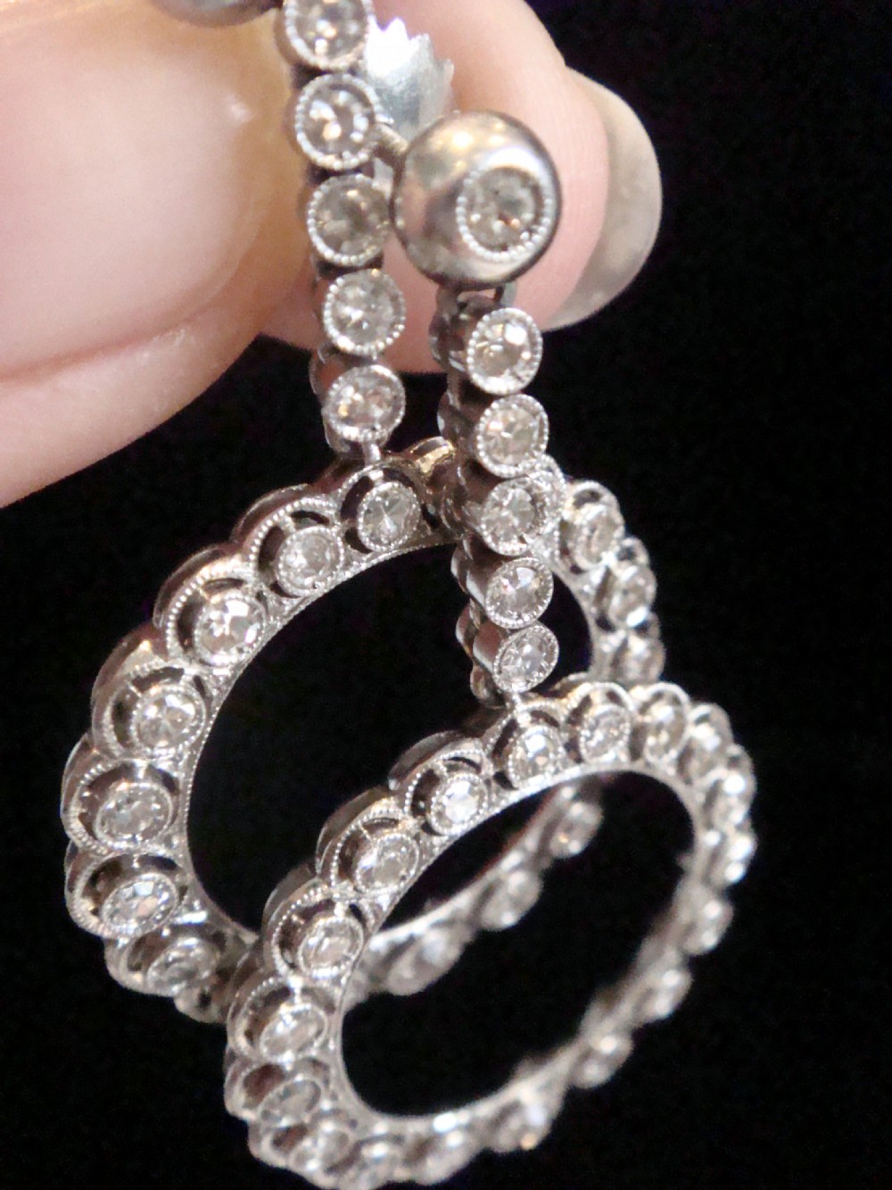 Pair of Edwardian style platinum and 18ct white gold drop earrings featuring circular halo pendants set with old cut diamonds suspended from articulated linear stems. View IX