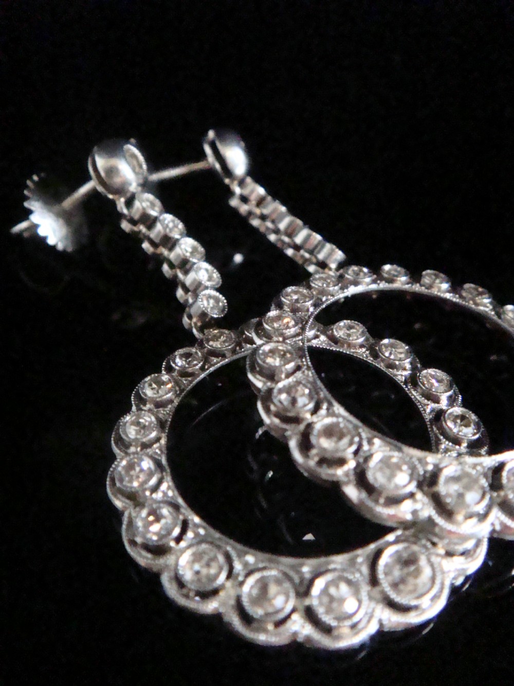 Pair of Edwardian style platinum and 18ct white gold drop earrings featuring circular halo pendants set with old cut diamonds suspended from articulated linear stems. View X