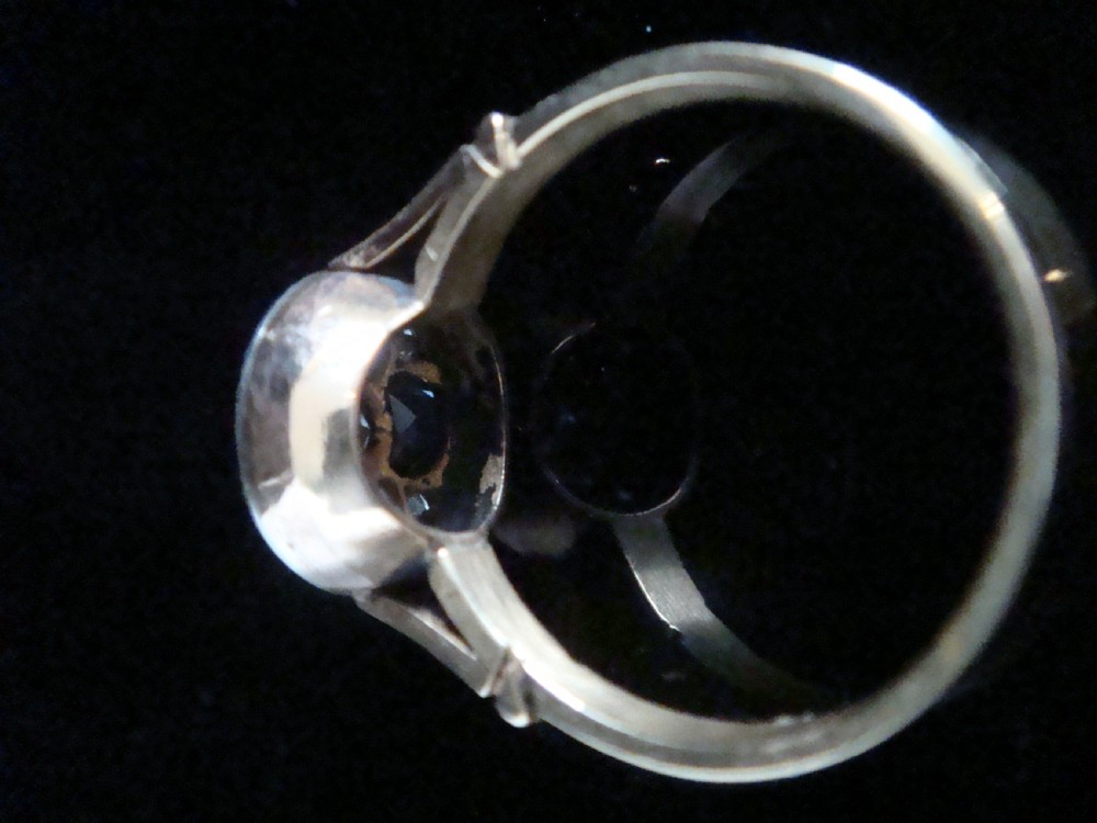 An Art Deco ring featuring a central round diamond surrounded by four dark blue sapphires arranged in a four-leaf clover motif with millegrain platinum borders and a gold shank. View IV