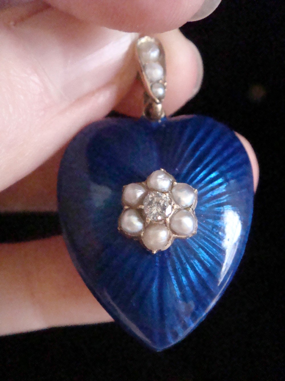 A Victorian heart-shaped pendant in cobalt blue guilloche enamel, accented by a central seed pearl and diamond star motif with a pearl-set gold bail.
