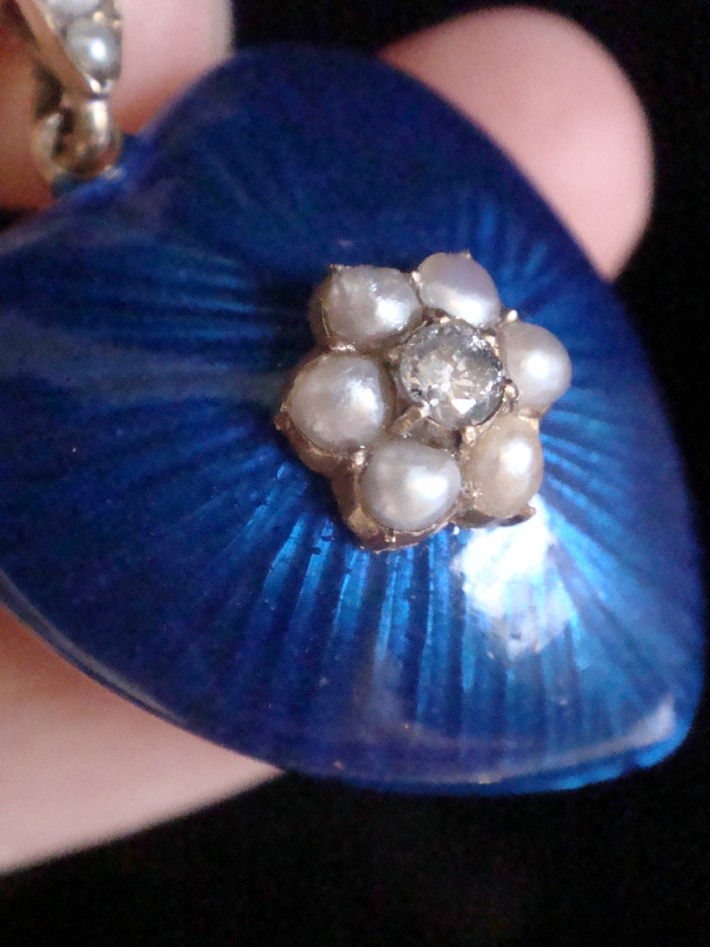 A Victorian heart-shaped pendant in cobalt blue guilloche enamel, accented by a central seed pearl and diamond star motif with a pearl-set gold bail. View II