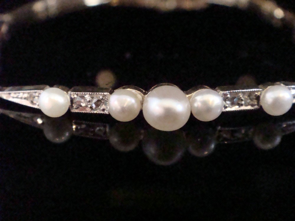 An Edwardian 18ct yellow gold line bracelet featuring a central row of five graduated saltwater pearls interspersed with diamond-set rectangular links. View II