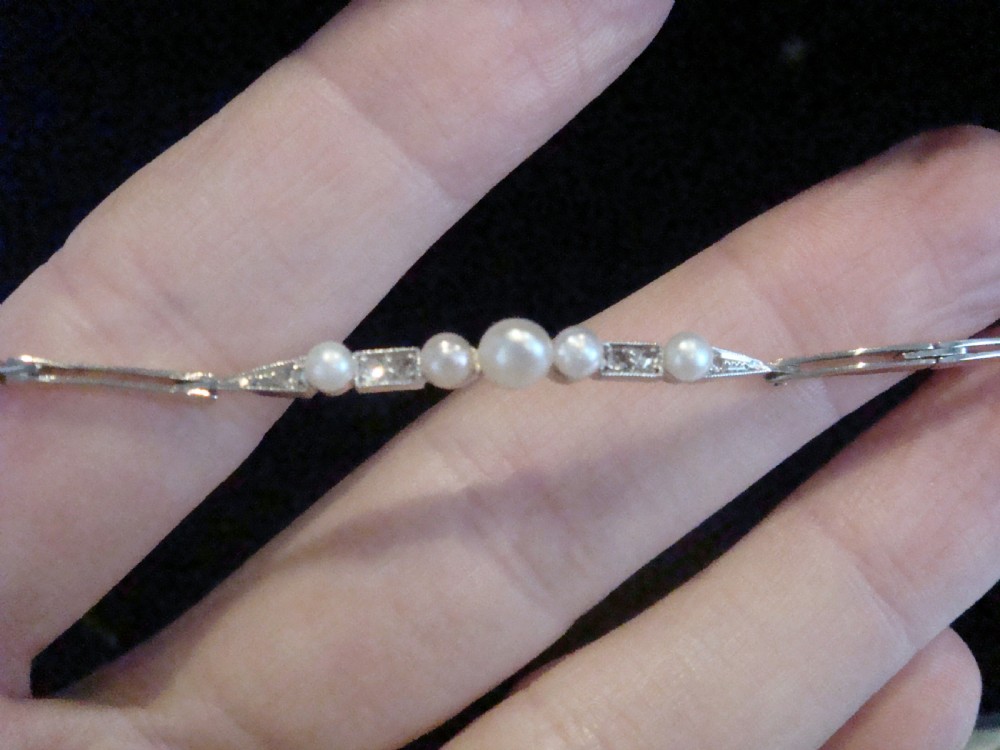 An Edwardian 18ct yellow gold line bracelet featuring a central row of five graduated saltwater pearls interspersed with diamond-set rectangular links. View IV