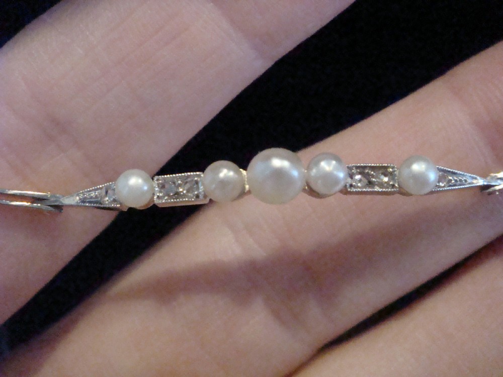 An Edwardian 18ct yellow gold line bracelet featuring a central row of five graduated saltwater pearls interspersed with diamond-set rectangular links. View VI