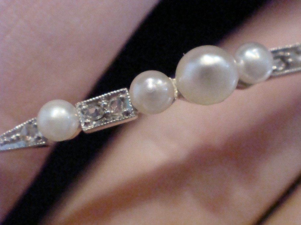 An Edwardian 18ct yellow gold line bracelet featuring a central row of five graduated saltwater pearls interspersed with diamond-set rectangular links. View VII