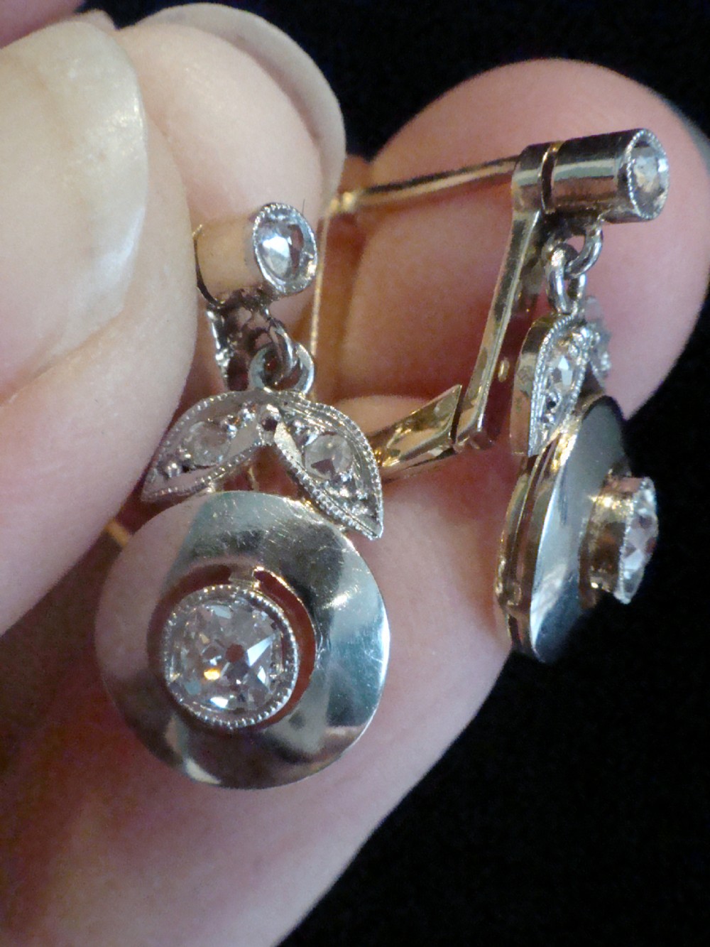 A pair of French Edwardian 18ct yellow gold and platinum drop earrings featuring central old-cut diamonds set within circular dished mounts with millegrain edges. View II