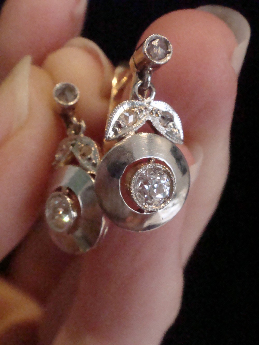 A pair of French Edwardian 18ct yellow gold and platinum drop earrings featuring central old-cut diamonds set within circular dished mounts with millegrain edges. View III