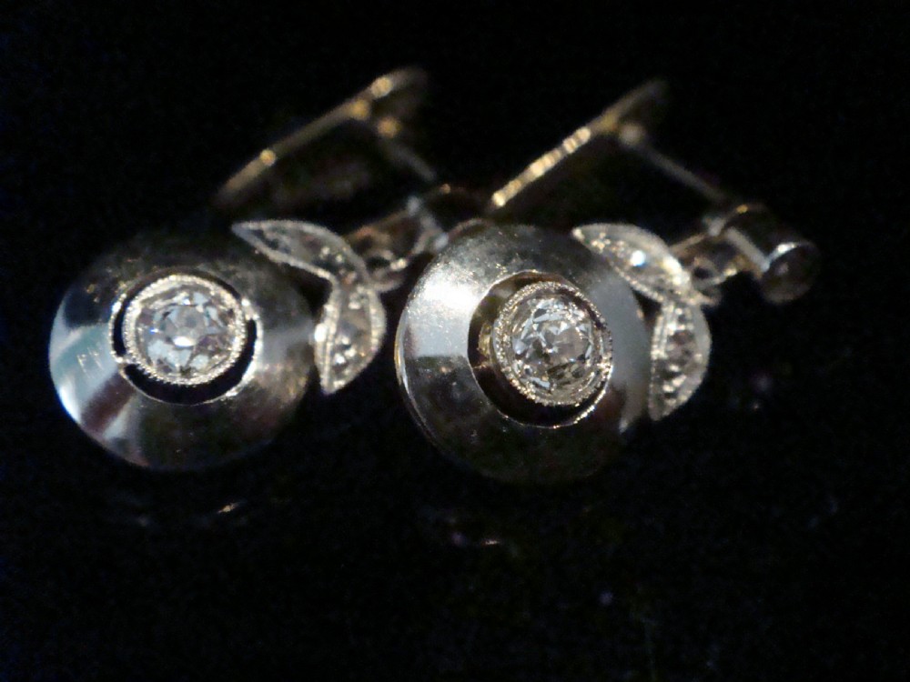 A pair of French Edwardian 18ct yellow gold and platinum drop earrings featuring central old-cut diamonds set within circular dished mounts with millegrain edges. View IV
