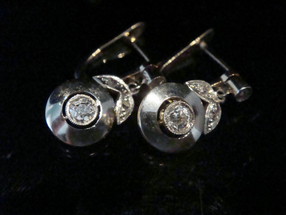 A pair of French Edwardian 18ct yellow gold and platinum drop earrings featuring central old-cut diamonds set within circular dished mounts with millegrain edges. View V