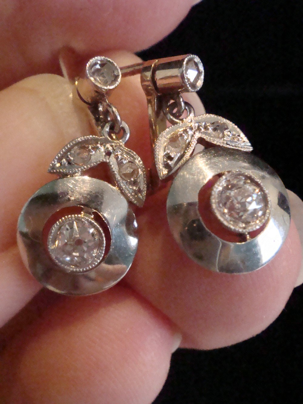 A pair of French Edwardian 18ct yellow gold and platinum drop earrings featuring central old-cut diamonds set within circular dished mounts with millegrain edges. View VI