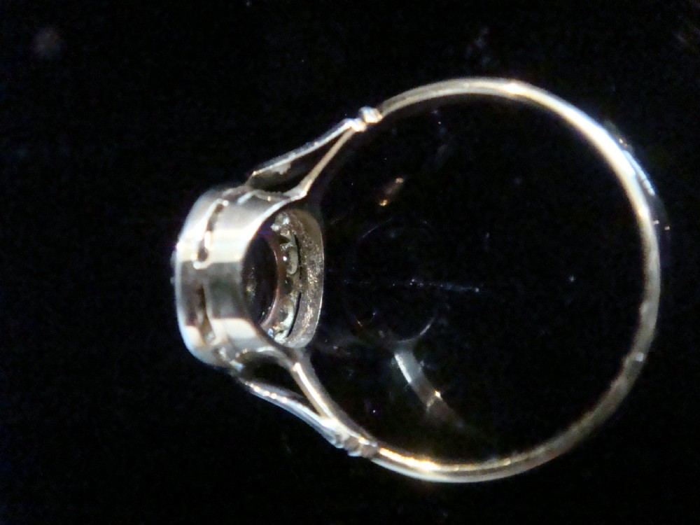 An Edwardian platinum and 18ct yellow gold cluster ring featuring a central oval cabochon sapphire surrounded by a halo of rose cut diamonds. View IV