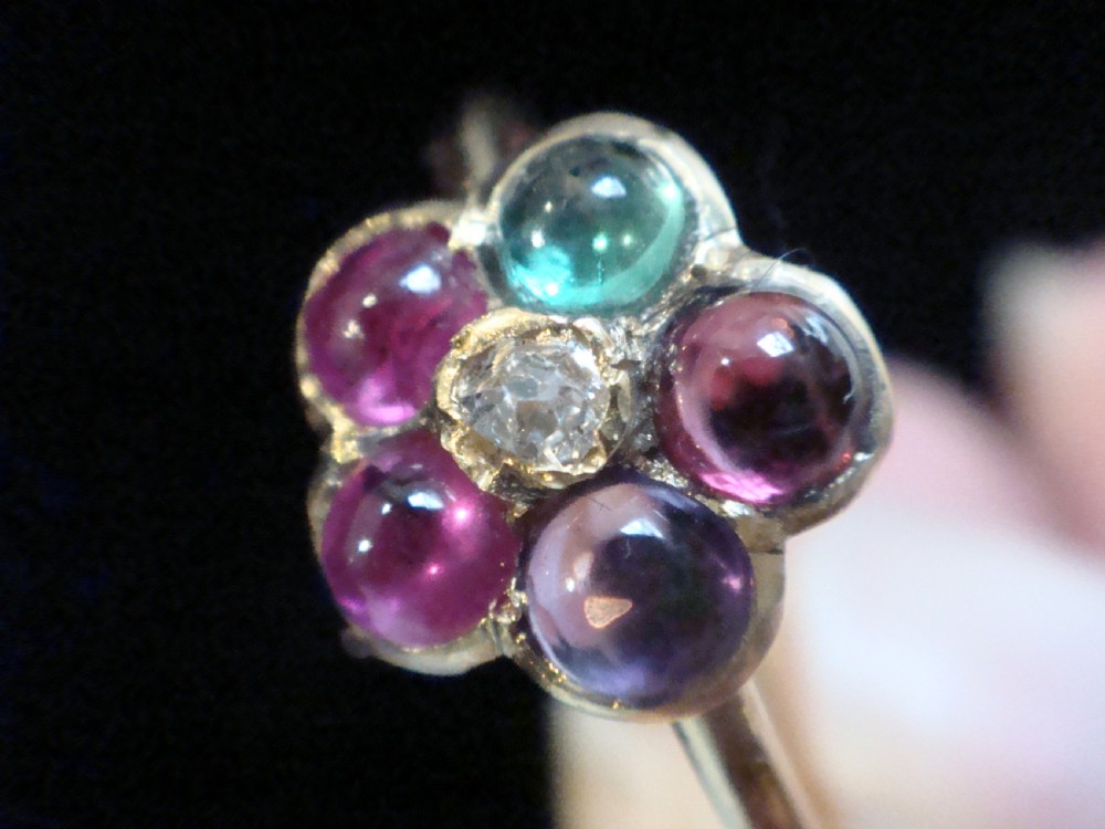 A Victorian 15ct gold flower cluster ring set with cabochon gemstones surrounding a central diamond. View II