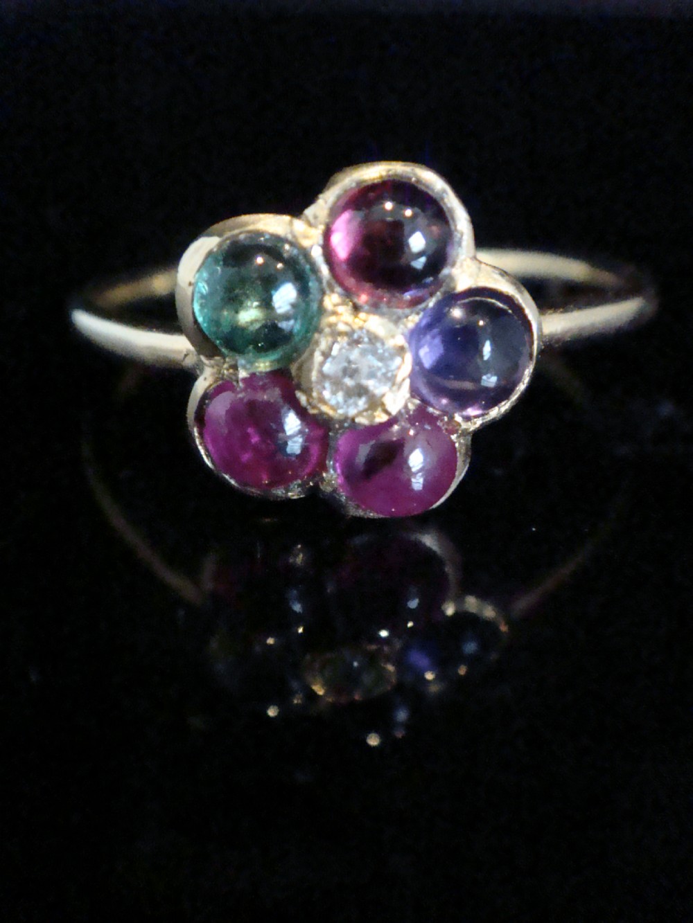 A Victorian 15ct gold flower cluster ring set with cabochon gemstones surrounding a central diamond. View IV