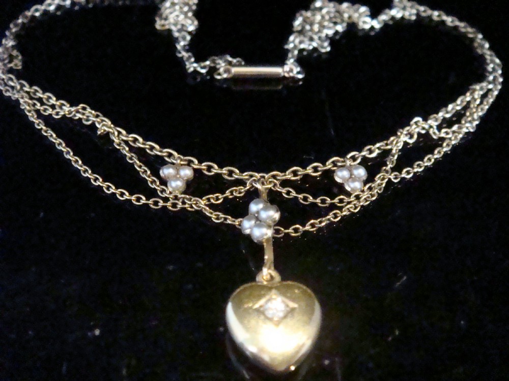 A Victorian yellow gold lavaliere necklace featuring draped swag chains, seed pearl clusters, and a central heart pendant inset with a diamond. View II