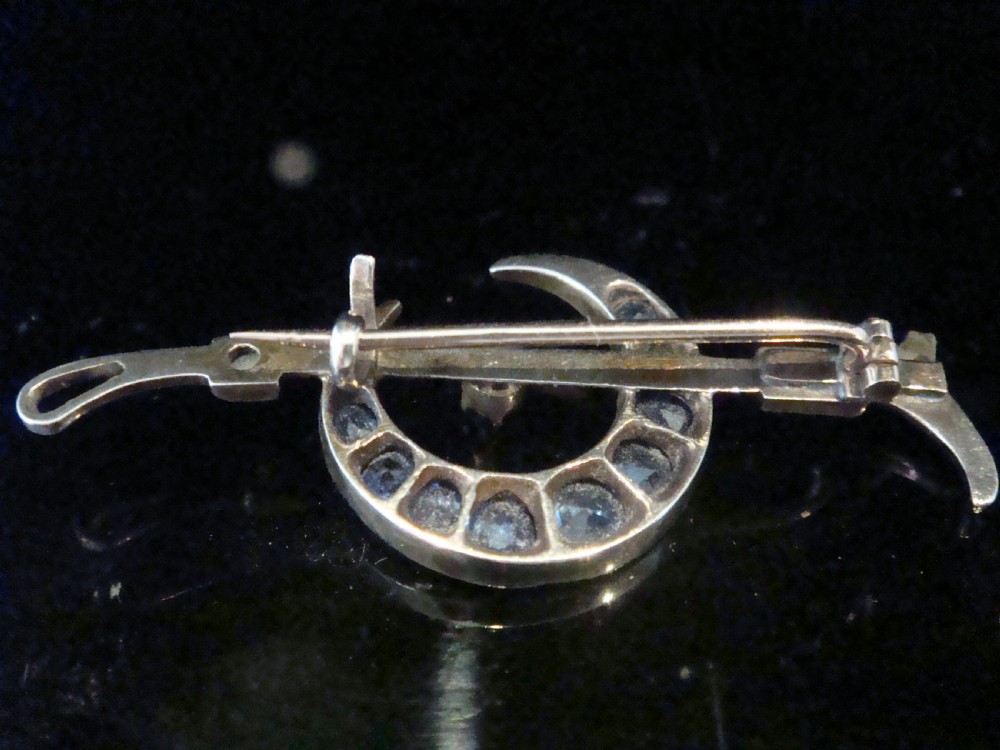 An Edwardian 9ct yellow gold bar brooch featuring a crescent moon motif set with blue sapphires and accented with seed pearls. View IV