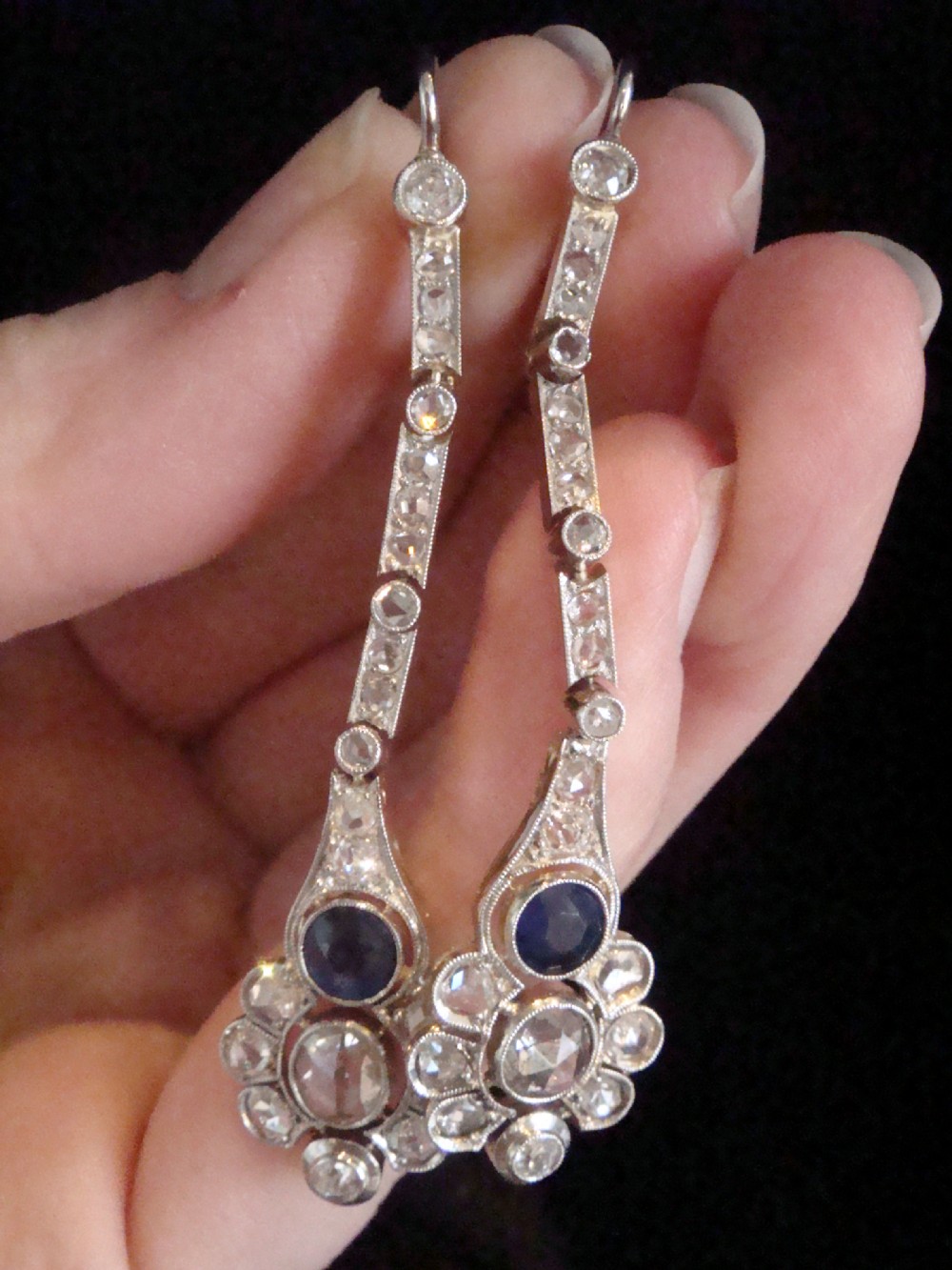 A pair of Edwardian drop earrings set in platinum featuring blue sapphires and old cut diamond floral clusters. View IV