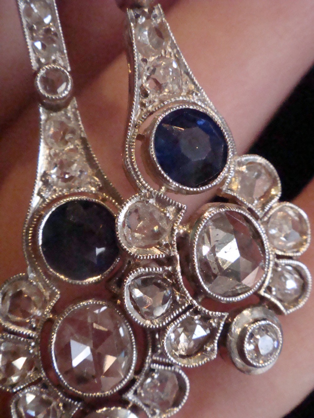 A pair of Edwardian drop earrings set in platinum featuring blue sapphires and old cut diamond floral clusters. View VII