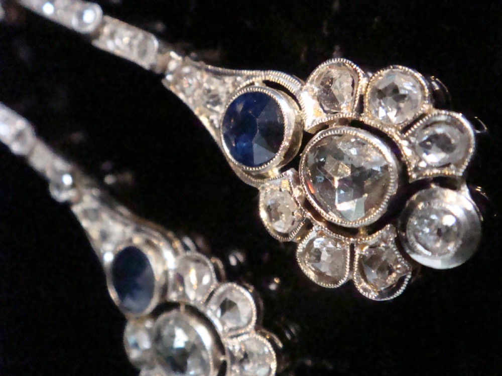 A pair of Edwardian drop earrings set in platinum featuring blue sapphires and old cut diamond floral clusters. View IX