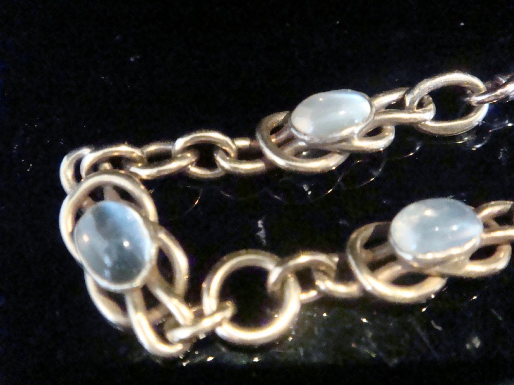 An Edwardian 9ct rose gold chain bracelet featuring lovers knot links set with oval moonstone cabochons. View II