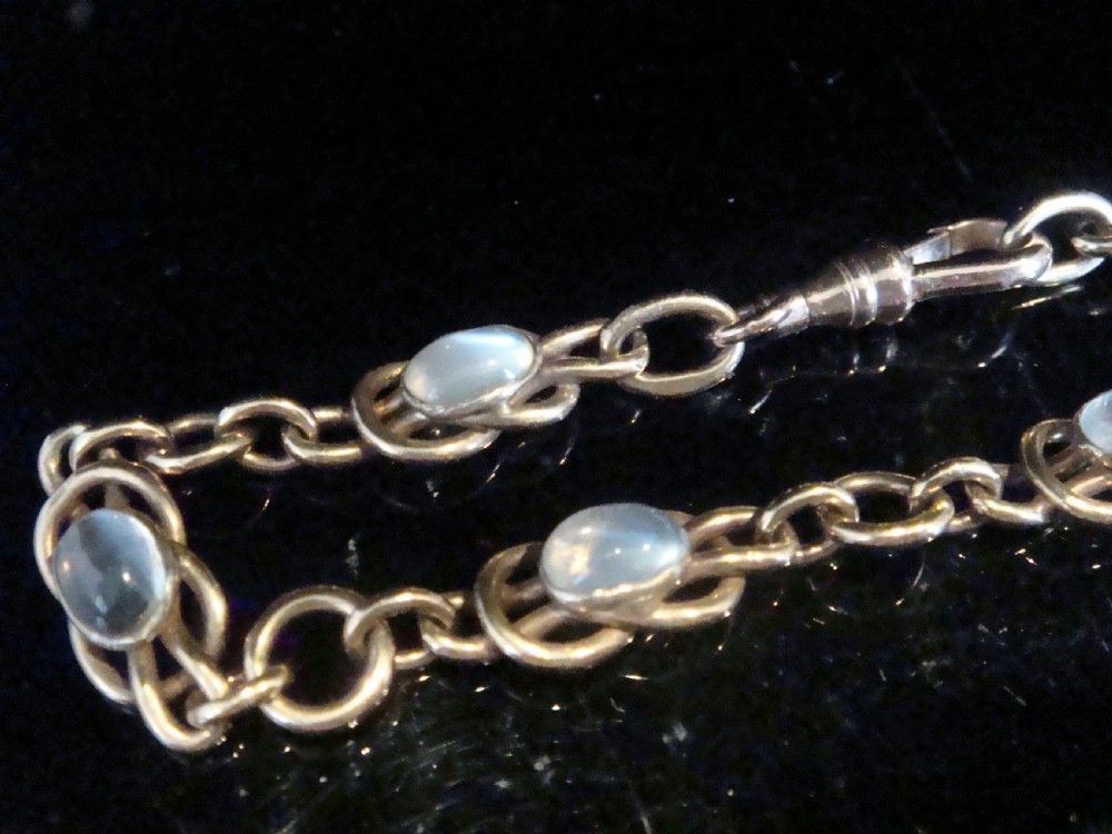 An Edwardian 9ct rose gold chain bracelet featuring lovers knot links set with oval moonstone cabochons.