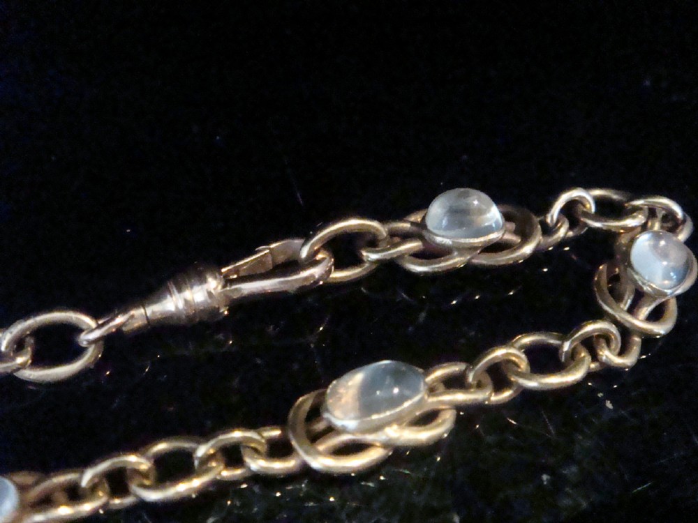 An Edwardian 9ct rose gold chain bracelet featuring lovers knot links set with oval moonstone cabochons. View IV