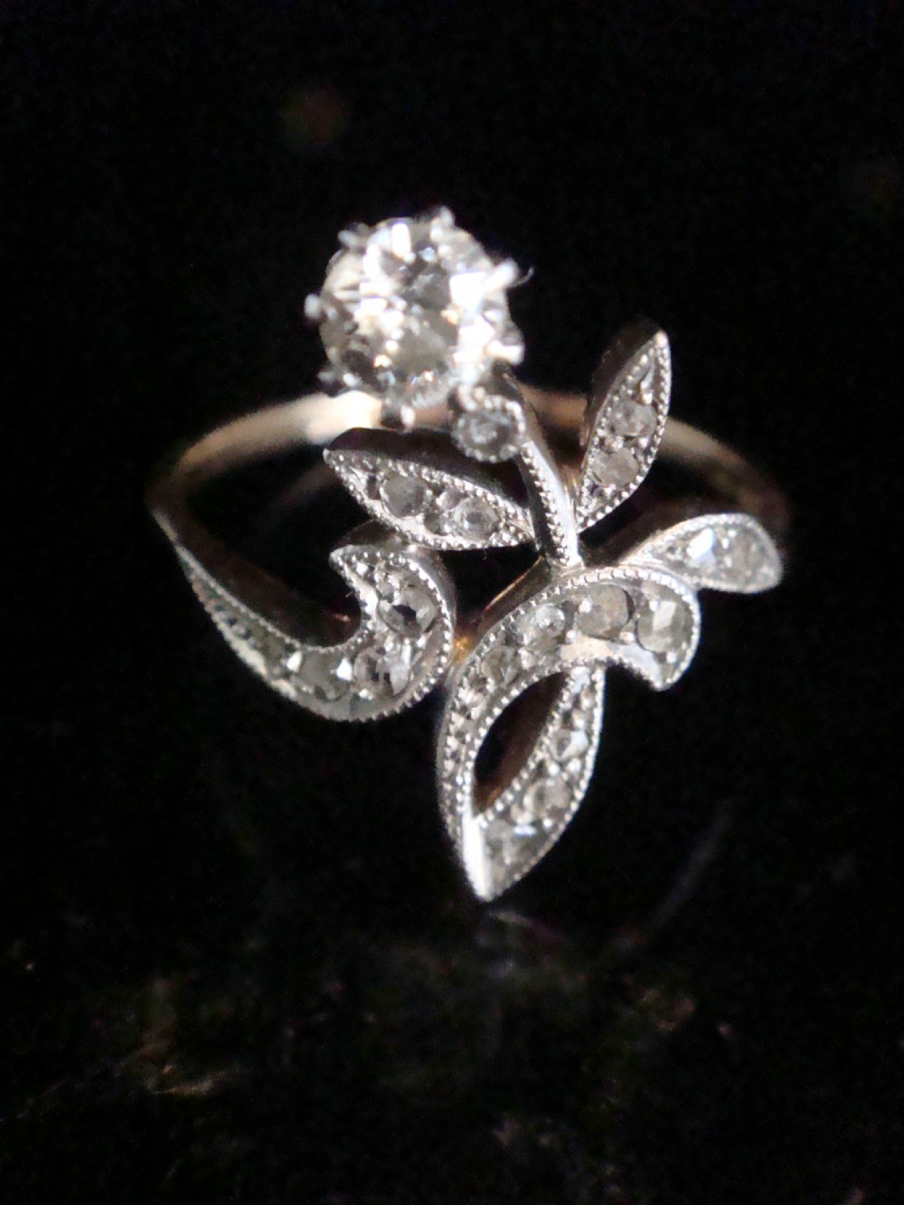 An Edwardian floral-shaped ring crafted in yellow gold and platinum, set with a central old cut diamond surrounded by diamond-encrusted leaf motifs. View II