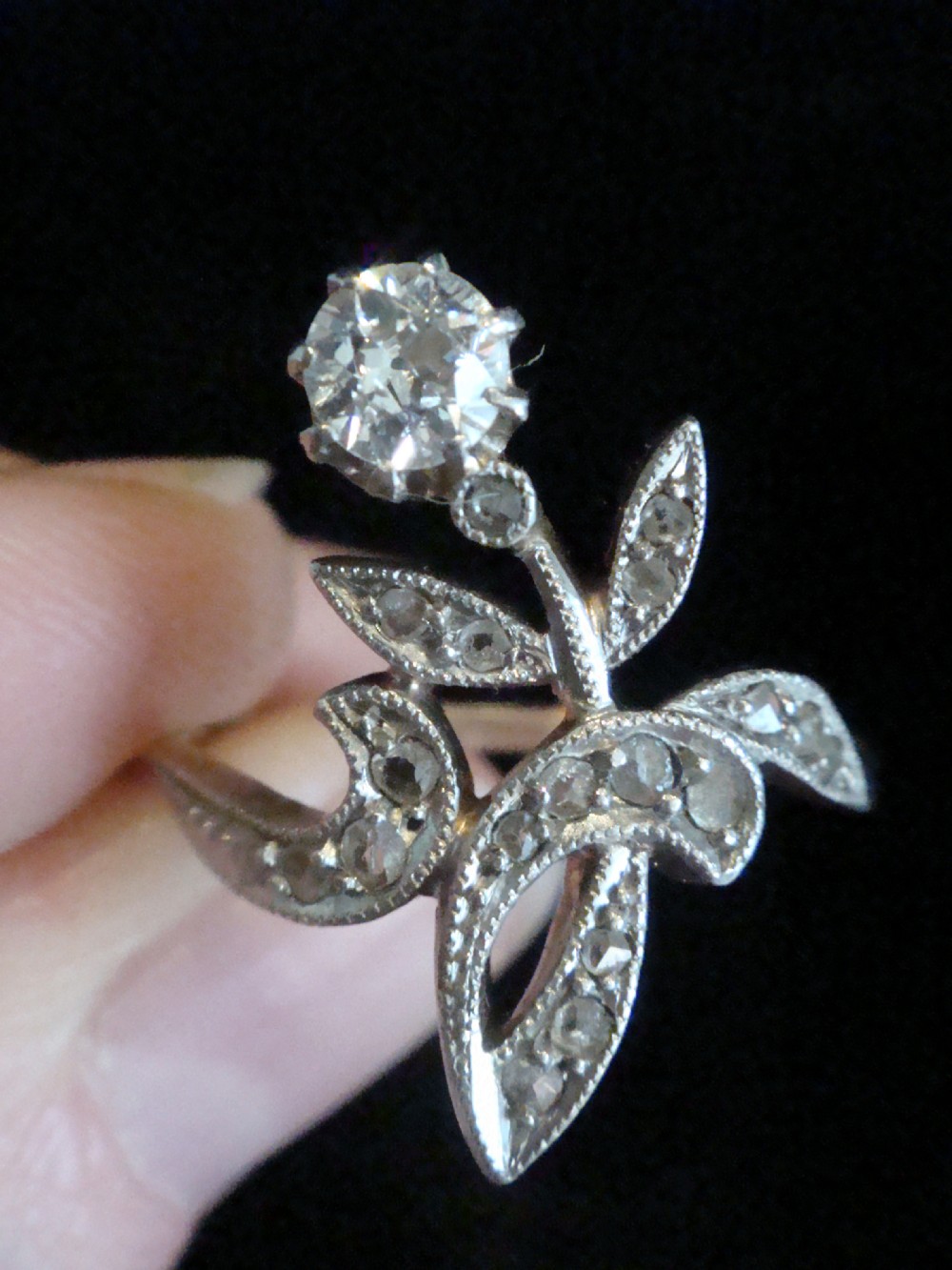 An Edwardian floral-shaped ring crafted in yellow gold and platinum, set with a central old cut diamond surrounded by diamond-encrusted leaf motifs. View IV