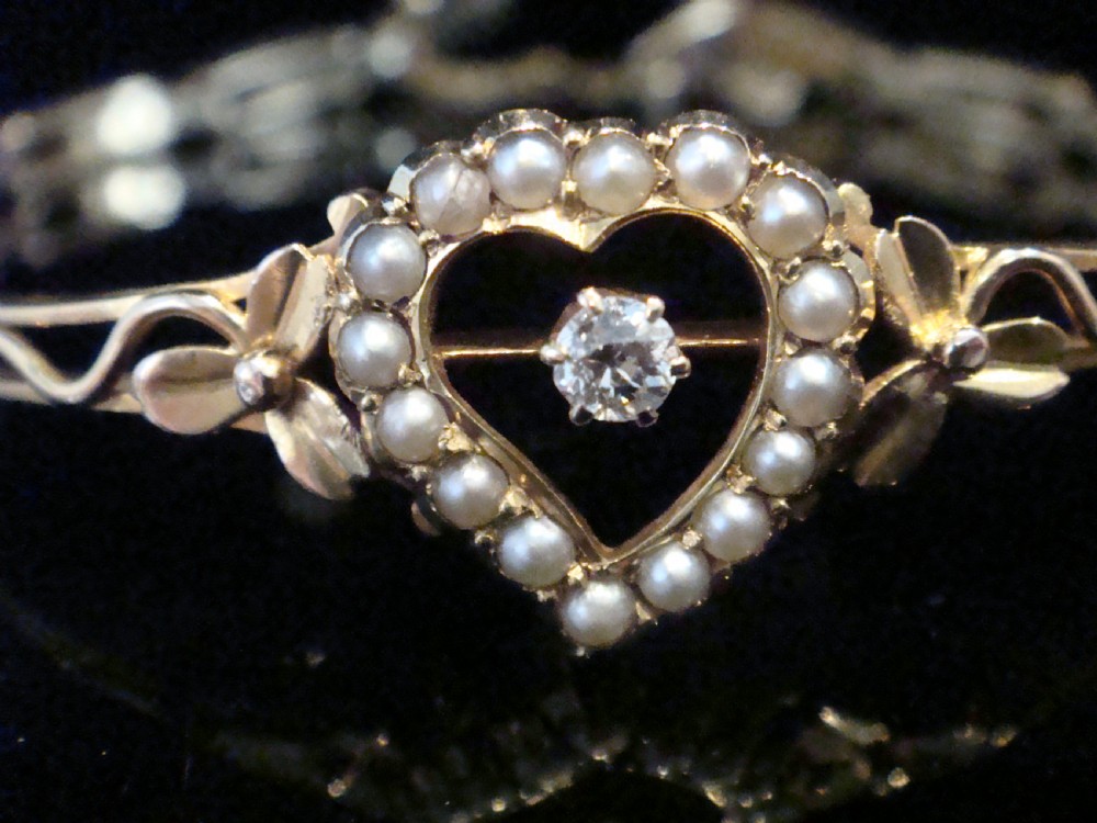 An Edwardian 9ct yellow gold bracelet featuring a central openwork heart set with seed pearls and a single diamond, flanked by sculpted foliage and wavy shoulders. View II