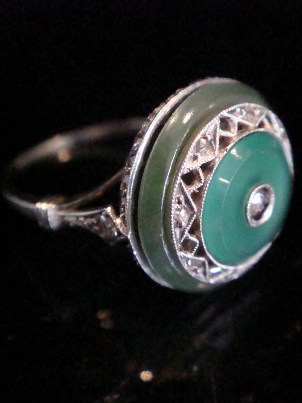 Circular Art Deco platinum target ring featuring a central old cut diamond surrounded by green chalcedony and milgrain pierced detailing. View II