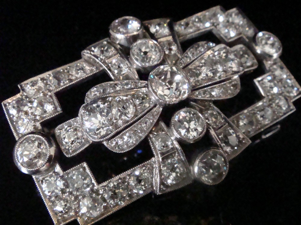 An Art Deco platinum brooch set with old cut diamonds featuring a central bow motif within a rectangular geometric frame. View II