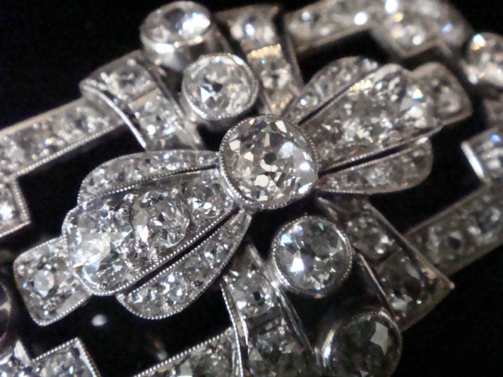 An Art Deco platinum brooch set with old cut diamonds featuring a central bow motif within a rectangular geometric frame. View III
