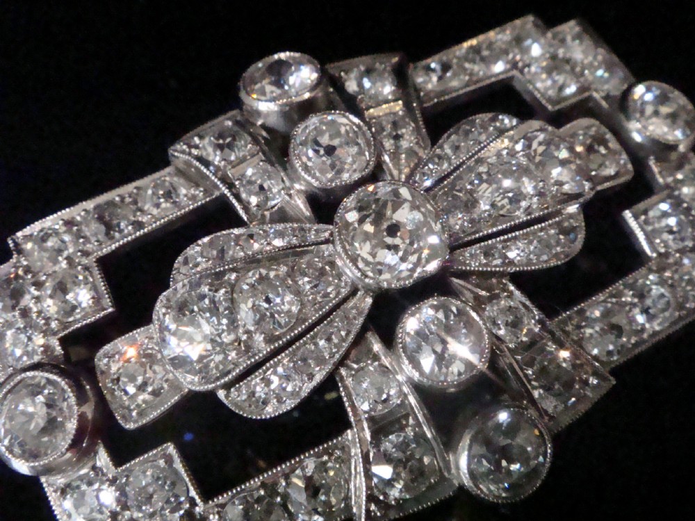 An Art Deco platinum brooch set with old cut diamonds featuring a central bow motif within a rectangular geometric frame. View IV