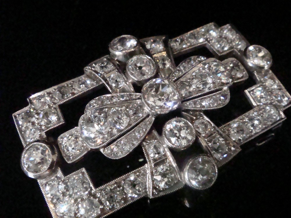An Art Deco platinum brooch set with old cut diamonds featuring a central bow motif within a rectangular geometric frame. View V