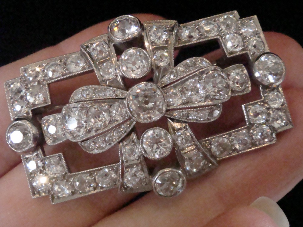An Art Deco platinum brooch set with old cut diamonds featuring a central bow motif within a rectangular geometric frame. View VI