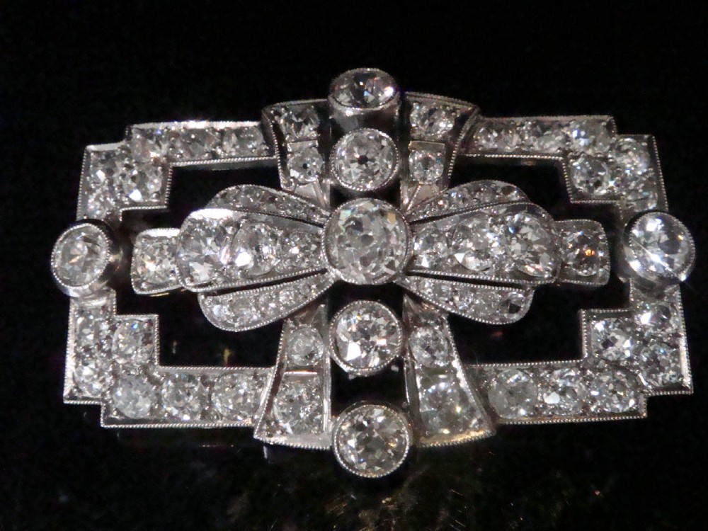 An Art Deco platinum brooch set with old cut diamonds featuring a central bow motif within a rectangular geometric frame. View VII