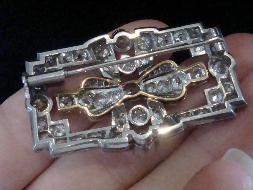 An Art Deco platinum brooch set with old cut diamonds featuring a central bow motif within a rectangular geometric frame. View VIII