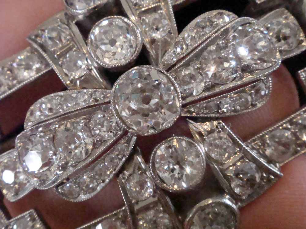 An Art Deco platinum brooch set with old cut diamonds featuring a central bow motif within a rectangular geometric frame. View IX
