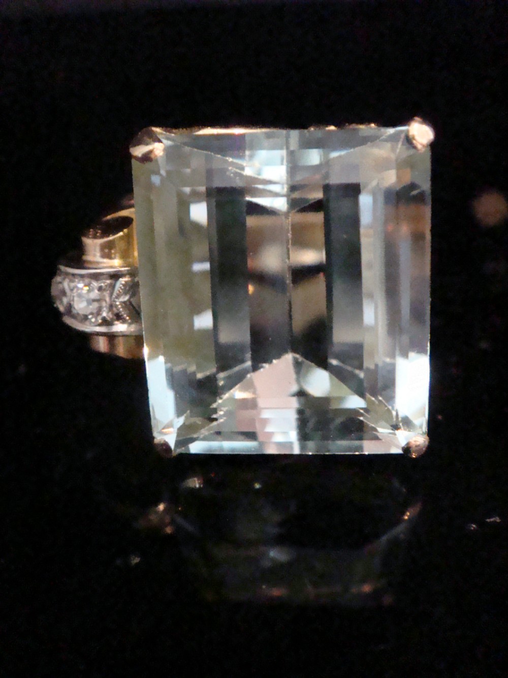 A Retro 18ct gold cocktail ring featuring a large rectangular step-cut pale blue aquamarine flanked by diamond-set tank shoulders. View II