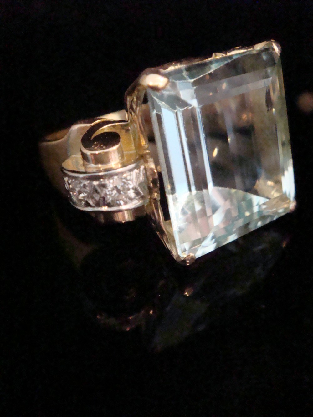 A Retro 18ct gold cocktail ring featuring a large rectangular step-cut pale blue aquamarine flanked by diamond-set tank shoulders. View III