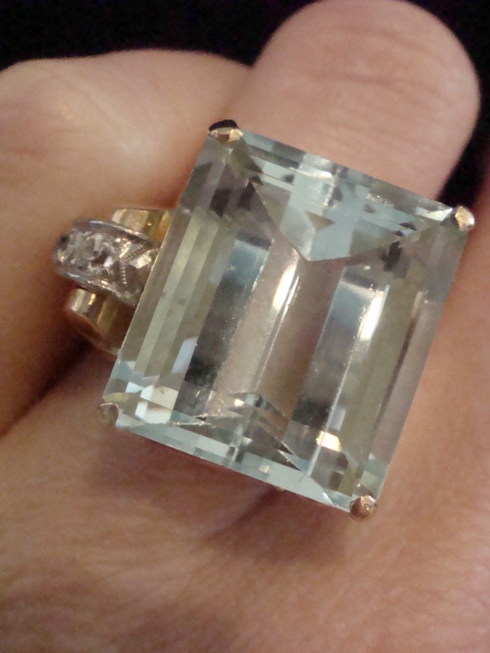 A Retro 18ct gold cocktail ring featuring a large rectangular step-cut pale blue aquamarine flanked by diamond-set tank shoulders. View V