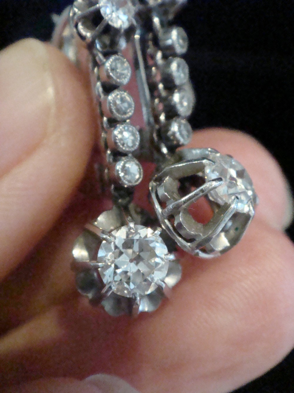 A pair of French Edwardian platinum and diamond drop earrings featuring transitional cut diamonds suspended in articulated settings. View VI