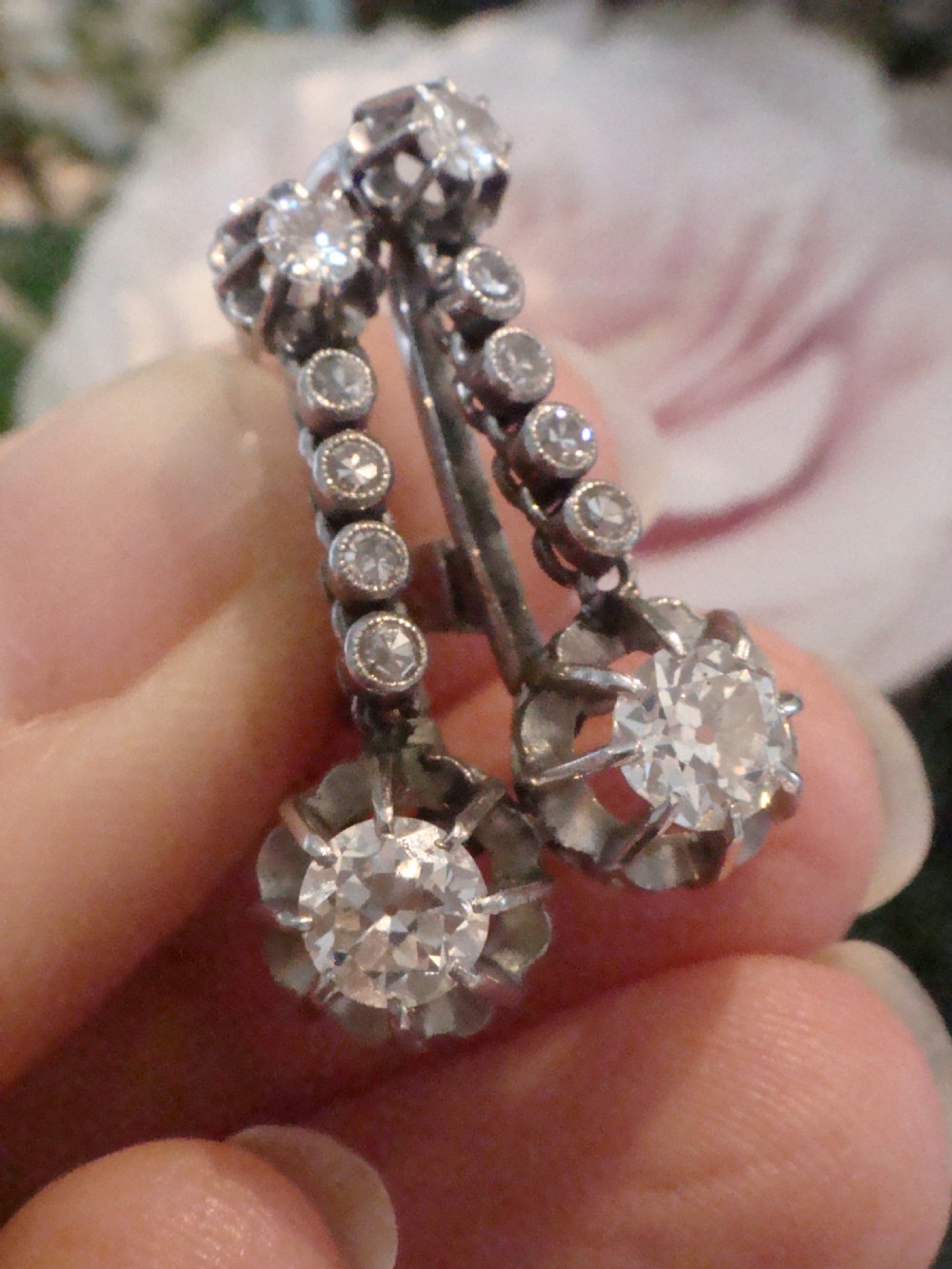 A pair of French Edwardian platinum and diamond drop earrings featuring transitional cut diamonds suspended in articulated settings. View VII