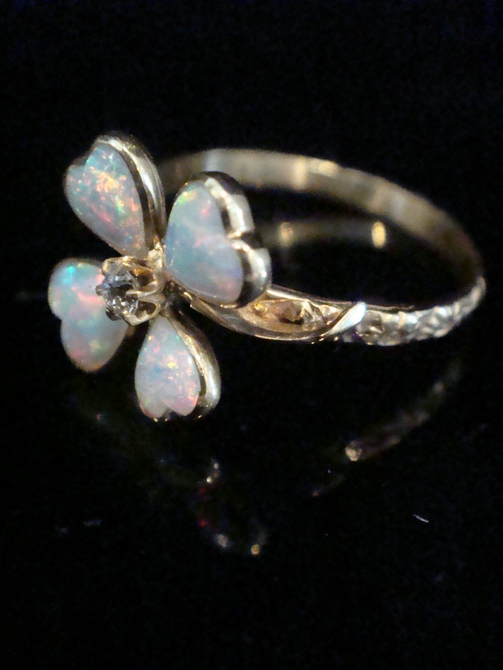 An Edwardian 18ct yellow gold ring featuring a four-leaf clover design composed of four heart-shaped opals surrounding a central round diamond. View III