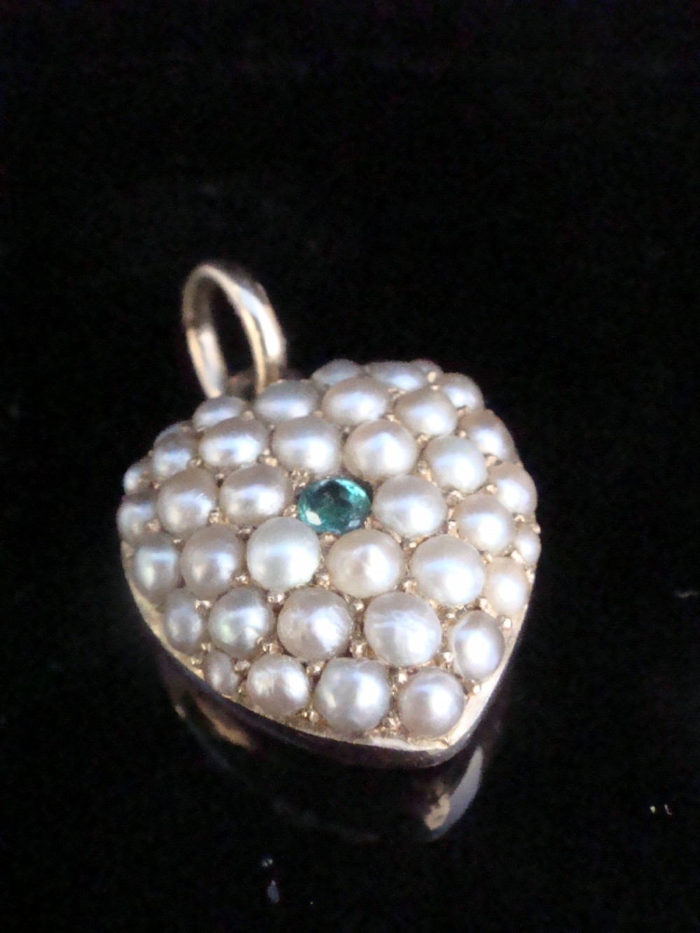 A Victorian heart-shaped 15ct yellow gold pendant encrusted with seed pearls around a single central emerald.