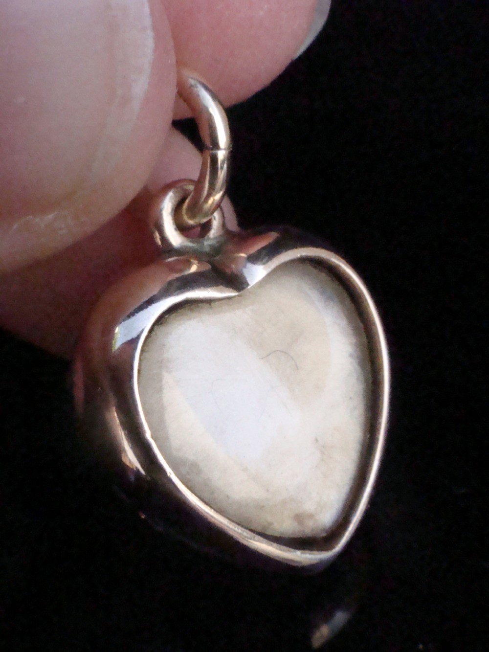 A Victorian heart-shaped 15ct yellow gold pendant encrusted with seed pearls around a single central emerald. View II